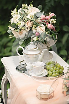 Romantic photo zone for the bride's wedding day gatherings. Table, flowers and rose petals in the forest