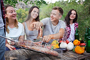 Happy friends in the park having picnic on a sunny day. Group of adult people having fun on a summer picnic.