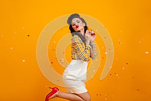 Romantic pinup girl dancing on yellow background. Studio shot of playful young lady in white skirt