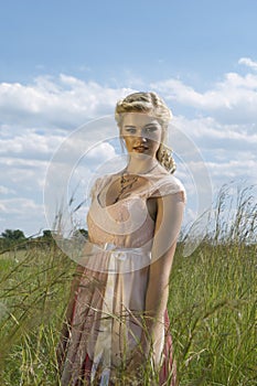 Romantic portrait of bohemian blonde in field of grass