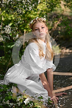 Romantic portrait of a girl in the park near a blooming apple tree. Natural cosmetics. Natural beauty of a woman in a white dress
