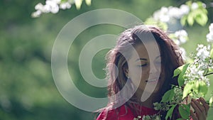 romantic portrait of positive woman in bloom garden at spring time, branches with white flowers