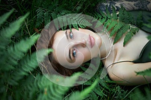 Romantic portrait of a woman in a fern in the forest. Art woman natural makeup resting in nature. Green fern thickets