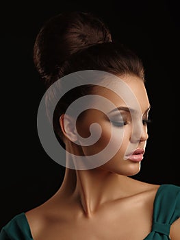 Romantic portrait of a young beautiful girl with mild features collected hair and expressive make up on the black background