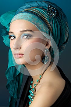 Romantic portrait of young woman in a turquoise turban on a beau