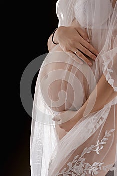 romantic and pregnancy photoshoot, young pregnant woman in white transparent dress on dark background, motherhood an