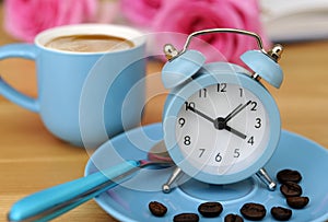 Romantic roses with blue espresso cup and coffee and alarm clock