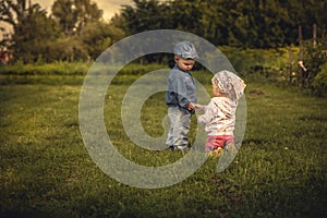 Romantic scene with couple of children boy and girl holding with hands at sunset in rural field symbolizing love and togetherness