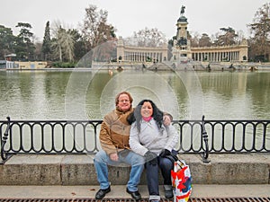 Romantic scene of a smiling middle-aged couple sitting on a step against the water of Grand Pond or Estanque Grande del Retiro par photo