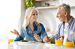 Romantic senior couple eating tasty breakfast together in kitchen at home