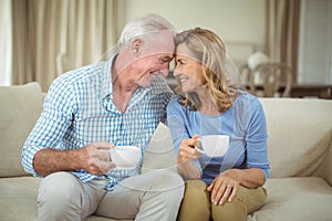 Romantic senior couple having cup of coffee in living room