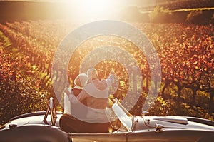 Romantic, senior couple and vintage car by countryside for wine tasting, sharing drink or memories together on vineyard