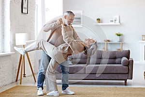 Romantic senior family couple wife and husband dancing to music together in living room