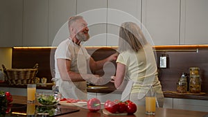 Romantic senior retired Caucasian family couple dancing waltz celebrate marriage anniversary cooking dinner old husband