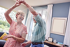 Romantic Senior Retired Couple Dancing In Lounge At Home Together