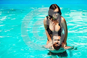 Romantic sensual couple relaxing in swimming pool. Bearded guy having fun with hot girlfriend. Summer vacation. Happy lovers