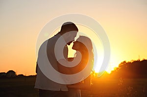 Romantic sensual young couple in love posing in field at the sun