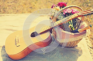 Romantic set, acoustic guitar, basket with wine, bouquet flowers on plaid. Romance, love, date, Valentines day concept