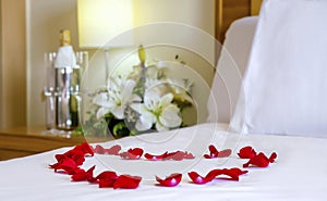 Romantic setup with honeymoon bed with focus on the heart-shaped rose petals