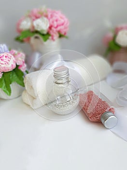 Romantic spa concept. Cosmetic pearl bottles, towel, bouquet of soap flowers on white background.