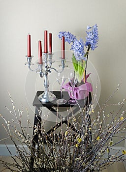 Romantic spring still life with candles, two wine glasses, blooming hyacinths and willow