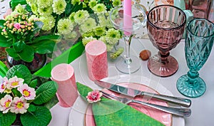 Romantic spring table setting for two with wine glasses, candles and flowers