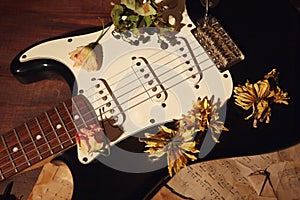 Romantic still with an electric guitar, dried flowers and vintage sheet music closeup