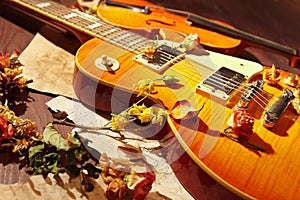 Romantic still life with a vintage electric guitar, rare violin, dried flowers and old sheet music closeup