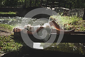 Romantic style young woman lie on small wooden bridge over pond