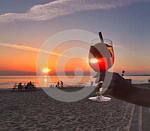 Romantic sunset Glass og orange limonade in young woman hand on front beach and sea on sky nature landscape