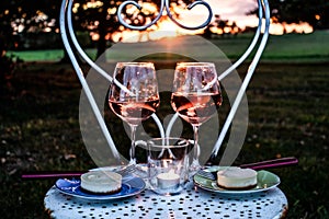 romantic sunset with two glasses of red wine, two pieces of cheesecake, a tealight