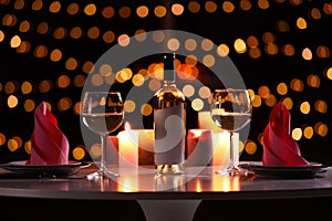 Romantic table setting with bottle of wine and burning candles
