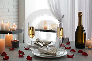 Romantic table setting with burning candles and rose petals
