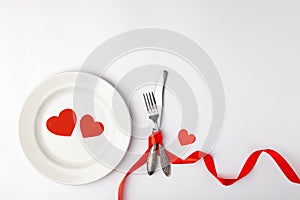 Romantic table setting on white background. Valentines day card template. Red ribbon, plate, silverware, vintage fork