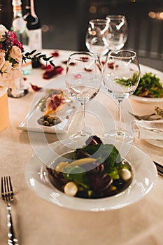 Romantic table setting with wine, beautiful flowers in box, empty glasses, rose petals and candles