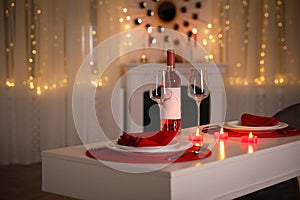 Romantic table setting with wine and candles for Valentine`s day dinner indoors