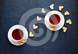 Romantic tea party for lovers on Valentines day. Sweet heart shaped cookies with two cups of tea on stone background.