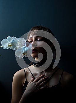 Romantic teen with orchid on black. Portrait of young lovely woman in flowers. Beauty Girl.