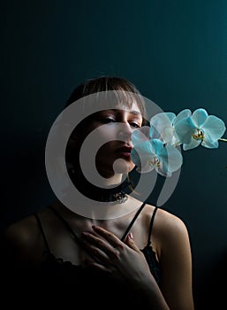 Romantic teen with orchid on black. Portrait of young lovely woman in flowers. Beauty Girl.