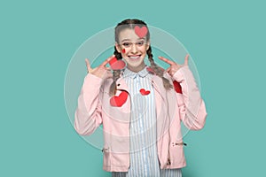 Romantic teenager girl standing pointing at little red heart on her body expressing happiness.