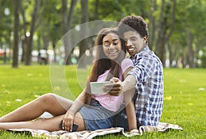 Romantic teenagers taking selfie on a date in park