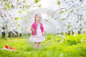 Romantic toddler girl eating apple in blooming garden