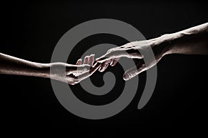 Romantic touch with fingers, love. Two hands stretch each other, black background. Couple in love holding hads, close up