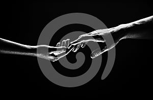 Romantic touch with fingers, love. Two hands stretch each other, black background. Couple in love holding hads, close up