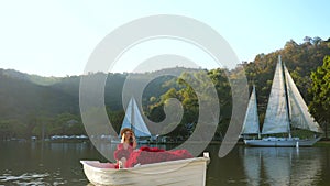 Romantic travel vacation. Stylish woman in red dress on date, sitting in boat