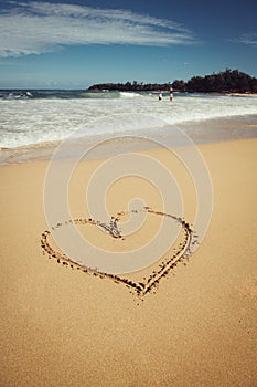 Romantic vacation on Hawaii concept. Heart drawn on ocean beach sand.