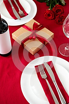 Romantic Valentine dinner for two table setting top view. Table with wine glass, gift box, tableware, fork, knife, rose flowers on