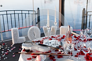 Romantic Valentine`s Day dinner setup with rose petals