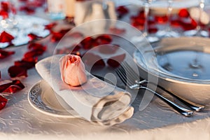 Romantic Valentine`s Day dinner setup with rose petals