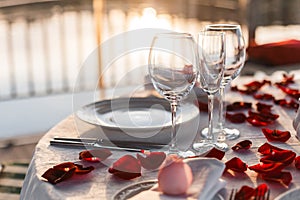 Romantic Valentine`s Day dinner setup with rose petals